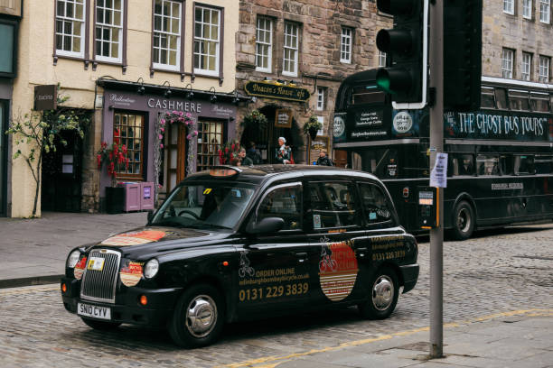 Edinburgh, United Kingdom - November 10, 2024: A black taxi navigates the cobblestone streets of Edinburgh, highlighting the vibrant atmosphere and historic architecture.