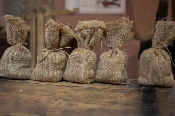 istock A row of small burlap sacks tied with twine, arranged on a rustic wooden surface, evoking a sense of vintage agriculture, traditional packaging, or organic storage. 2202263070