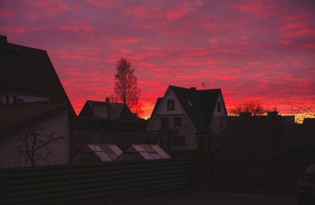 A white houses with a red sunset is in front. The house is surrounded by trees.