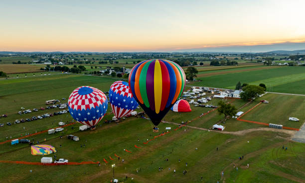 istock Colorful hot air balloons prepare for launch during sunset over expansive fields in a rural setting 2202272654