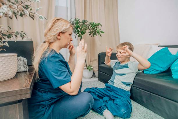 istock female therapist and boy practicing hand gestures in therapy session, cozy home setting, concept of child development and alternative communication 2202273832