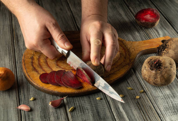 istock Hands skillfully slice vibrant beets on a wooden cutting board in a cozy kitchen setting. The rich colors and fresh ingredients create an inviting atmosphere for cooking 2202274941