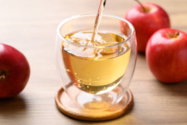 istock Apple cider pouring into glass with apple fruit on wooden background 2202277543