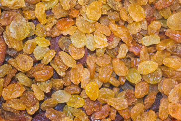 Dried golden raisins are arranged closely together, revealing their vibrant colors and textures, showcasing a healthy snack option often used in baking or cooking.