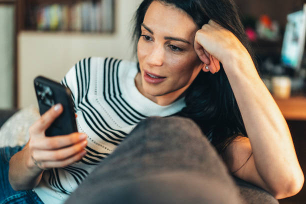 istock Engaged Woman Relaxing on a Couch with a Smartphone 2202280905