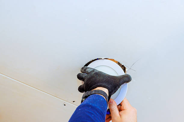 istock Hand installing a ceiling light fixture during home renovation project in a modern interior space 2202281376