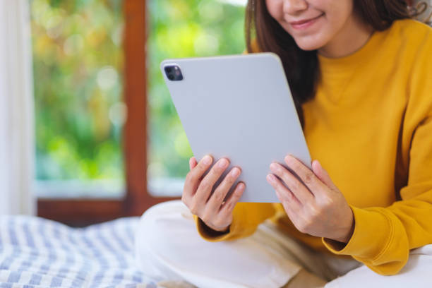 istock Closeup of a woman holding and using digital tablet while sitting on bed 2202288689