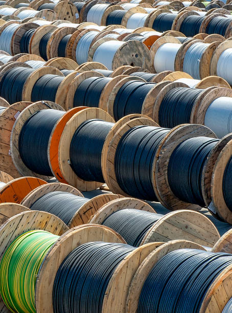 Large wooden spools tightly wrapped with industrial cables, showcasing the raw materials used in various construction and electrical projects. The sturdy wooden reels, often seen on job sites, emphasize the strength and durability required for heavy-duty tasks.