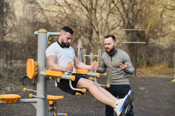 Fitness Instructor Motivating Male Client Counting His Reps While Doing Leg Raises