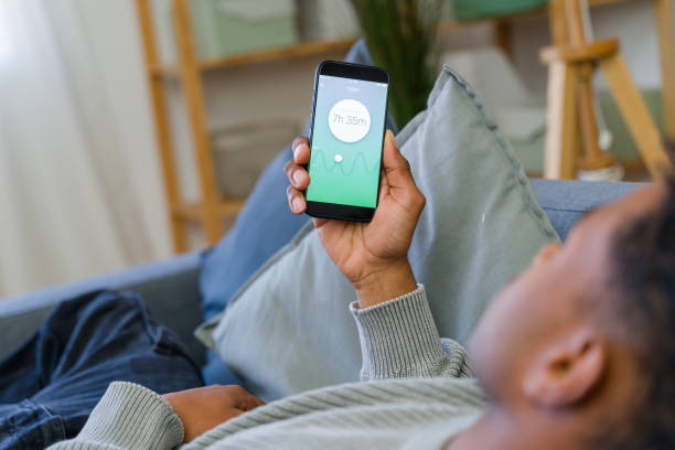 istock Man relaxing on sofa checking sleep tracking app on smartphone 2202292697