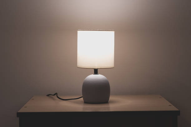 Modern night table lamp. Warm lighting from bedside lamp for reading books.