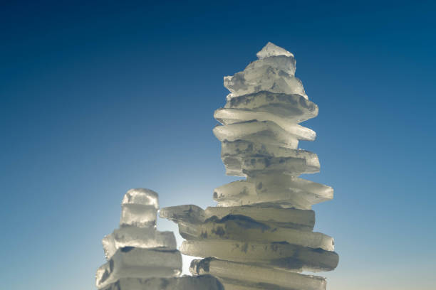 Ice shards stacked creating an intriguing formation against a clear blue sky, capturing the beauty and fragility of nature