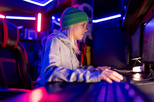 istock Focused female gamer playing video game on computer in gaming room 2202299176
