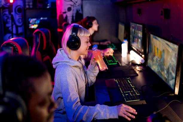 istock Young female gamer drinking energy drink while playing video games 2202299361