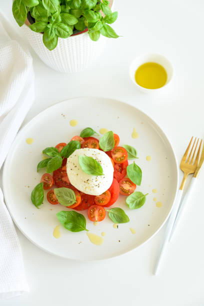 istock Salad Caprese with tomato, cherry, mozzarella and basil leaves on white wooden table 2202300465