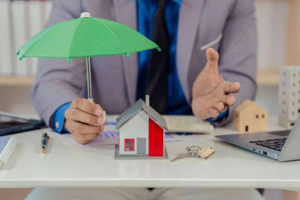 istock The model home has a green umbrella in its hand. Where home insurance is kept The image emphasizes safety protection. Suitable for insurance companies, close-up photos 2202301558