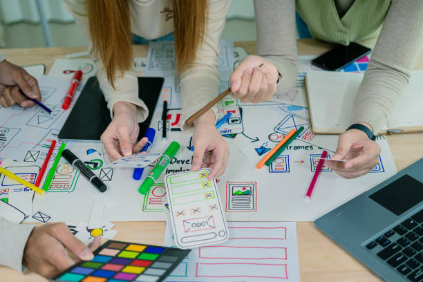 istock UX/UI designers discuss and brainstorm layouts for website and mobile app prototypes in website and application design ideas. Close-up. 2202304383