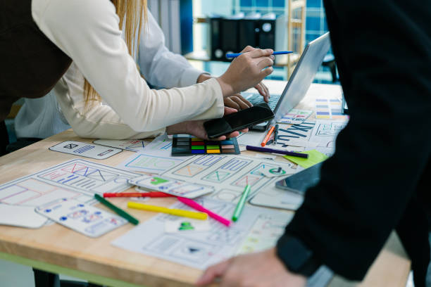 istock UX/UI designers discuss and brainstorm layouts for website and mobile app prototypes in website and application design ideas. Close-up. 2202304418