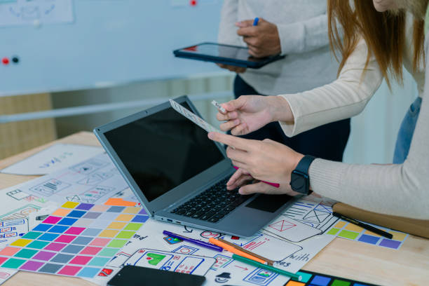 istock UX/UI designers discuss and brainstorm layouts for website and mobile app prototypes in website and application design ideas. Close-up. 2202304425