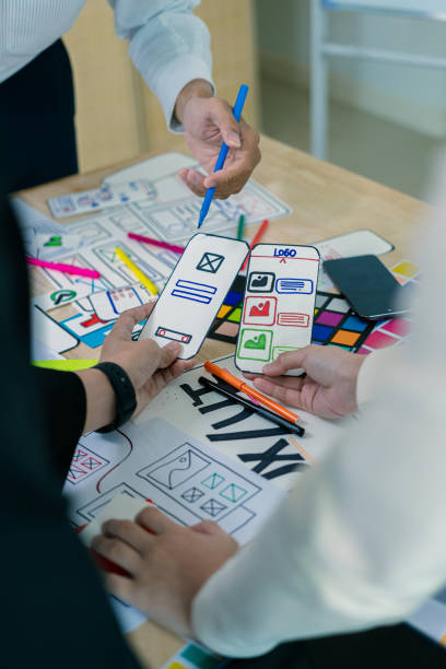 UX/UI designers discuss and brainstorm layouts for website and mobile app prototypes in website and application design ideas. Close-up.