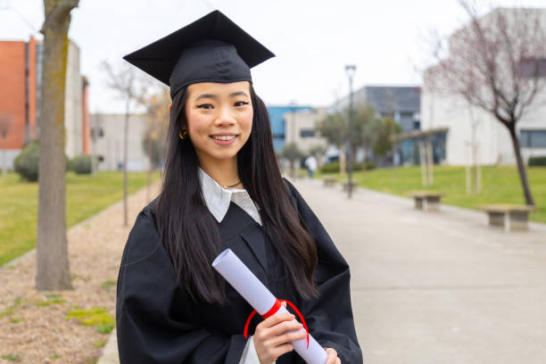 istock Young graduate smiling and holding her diploma in university campus 2202305803