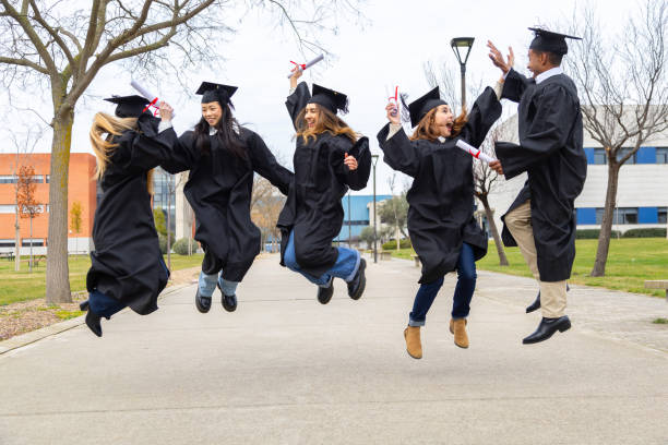 Group of cheerful multiethnic graduates jumping together holding their diplomas on graduation day