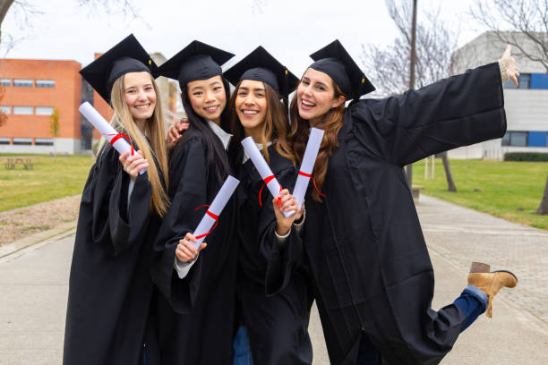 istock Happy graduating students holding diplomas celebrating outside university 2202305827