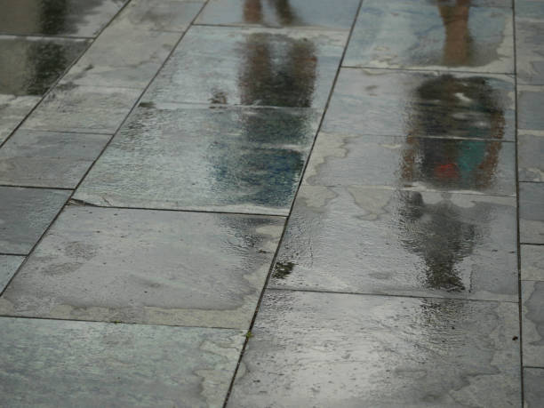 istock reflection of two people walking on a pavement wet from rain 2202306409