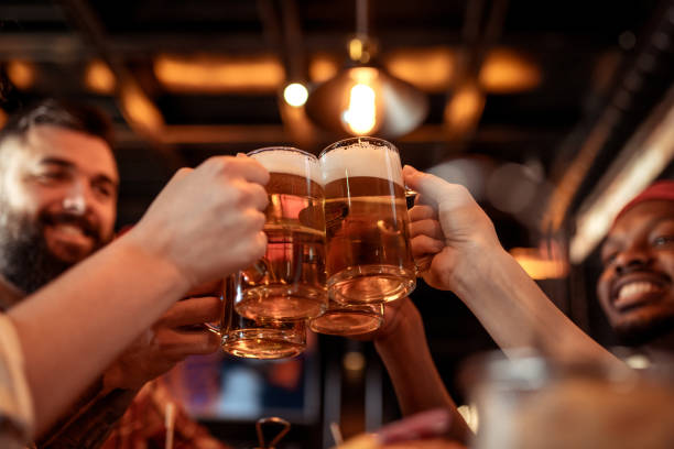 istock Cheers to Friendship: Group Toasting with Beer Mugs in a Cozy Bar 2202307266