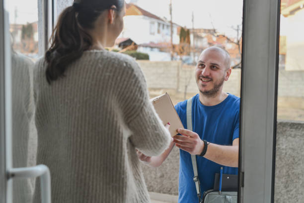 istock Female Customer Receiving Package from Delivery Guy While Standing at Her Front Door 2202309451