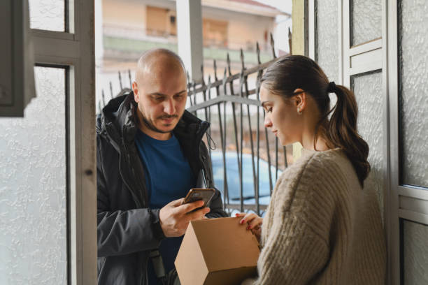 istock Delivery Guy Scanning Barcode Using Phone to Confirm Package Delivery to Female Customer 2202310128