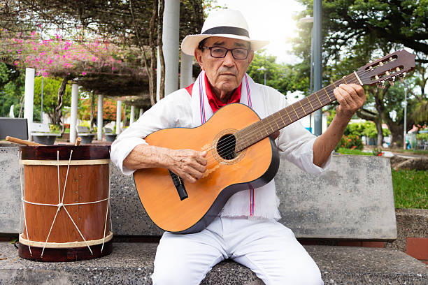 istock Mature colombian man sitting with a guitar and a typical andean drum 2202311031