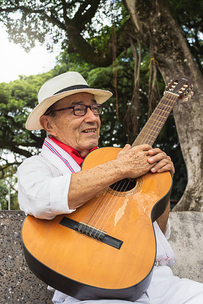 istock Mature man sitting with a guitar in a public park 2202312741