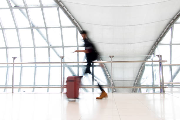 istock An unidentifiable person walking in motion blur on white corridor with large windows. Blurred people walking in a modern building. 2202314000