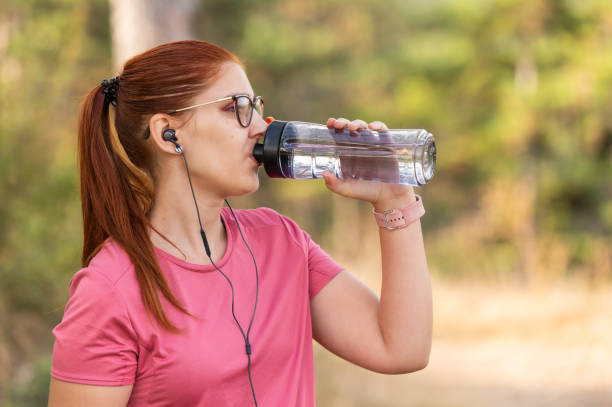 istock Active woman drinking water while listening to music 2202319467