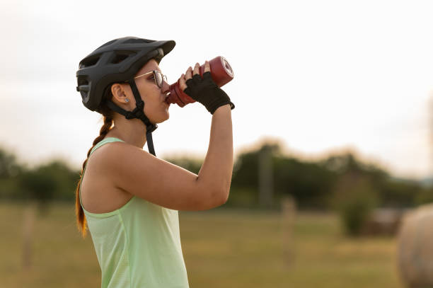 istock Female cyclist drinking water outdoors 2202319499