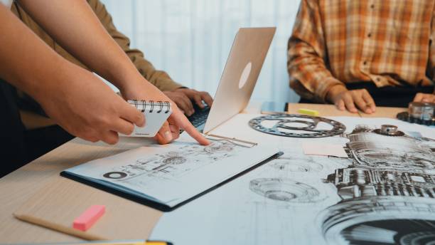 istock Collaborative Team Meeting on Engineering Designs with Laptop, Sketches, Notepad, and Colorful Sticky Notes in Bright and Modern Office Space SACTR 2202319854