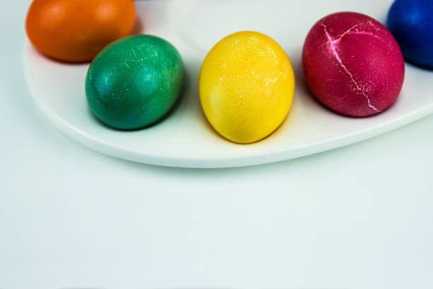 Colorful dyed easter eggs arranged on a white plate. multicolored eggs in bright hues of yellow, purple, green, and blue. Color contrast, creativity, holiday decoration. Copy space. Selective focus