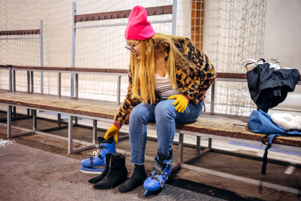 Female adult putting ice skating boots on and preparing for ice skating while sitting