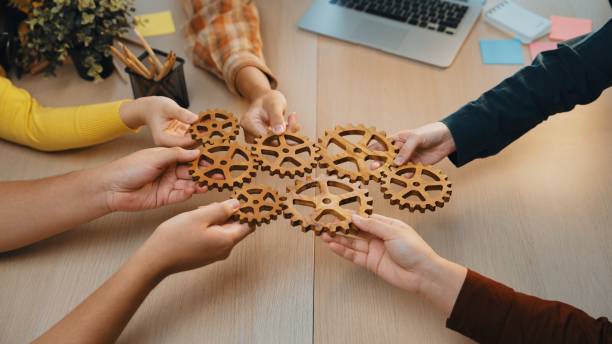 Collaborative Teamwork with Wooden Gears Symbolizing Innovation and Strategy in a Workspace Environment SACTR