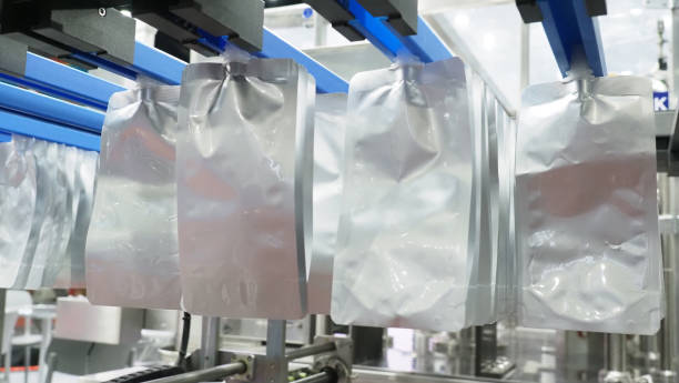 istock Automatic packaging machine filling silver spout pouches in a industrial production line. 2202321939