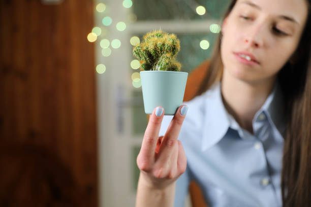A stunning young woman enjoying her time at home with a cactus in her hands.