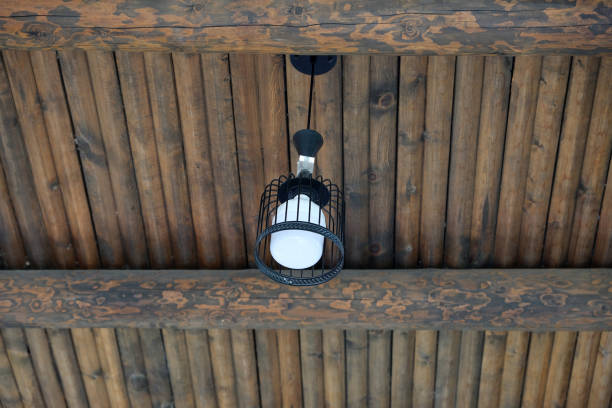 A stylish black cage light fixture hangs from a wooden ceiling, adding a touch of elegance to the rustic environment. The warm light enhances the natural wood tones