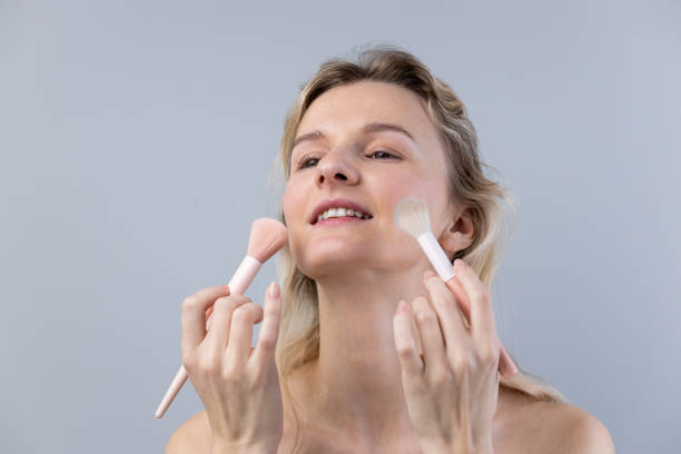 istock Woman applying makeup with brushes, showcasing a beauty routine that emphasizes the importance of good skincare and cosmetics application for a radiant look and self-expression. 2202327004
