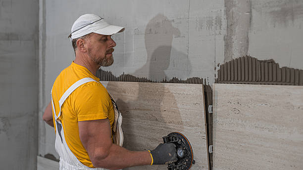 Tiling with large format tiles. A tiler placing a tile held by a tile suction cups.