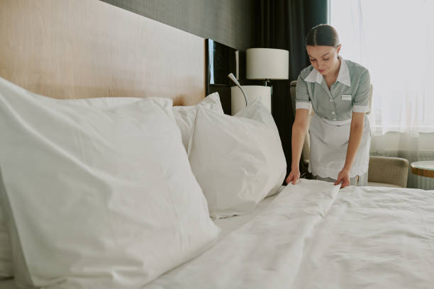 istock Maid in Uniform Making Bed in Hotel Room 2202327975