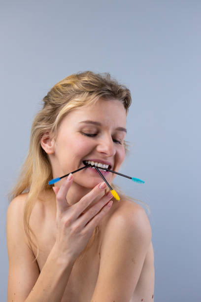 istock A Playful Portrait: A Model Smiling with Colorful Brushes in Her Mouth, Radiating Joy and Creativity in a Minimalist Setting 2202328387