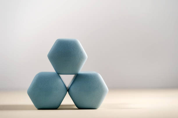 A group of hexagonal dumbbells is neatly arranged on a light background with copy space. Concepts of strength training and fitness activities. Ideal for workouts at home and health lifestyles.