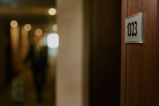 Medium close up of room number sign on wooden door in hotel