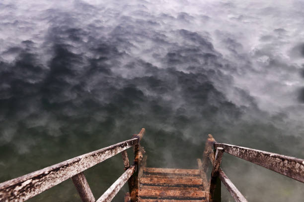 A staircase into a lake with the reflection of eerie clouds